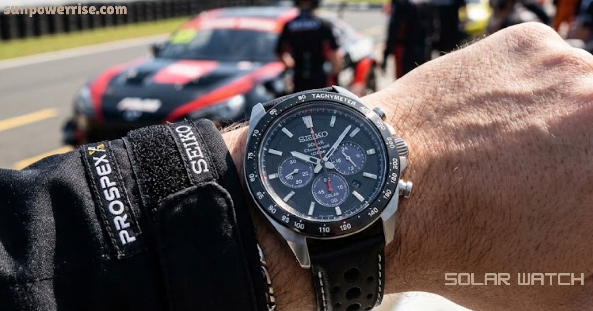 Solar watch worn on a wrist during a motorsport event with a sports car in the background.